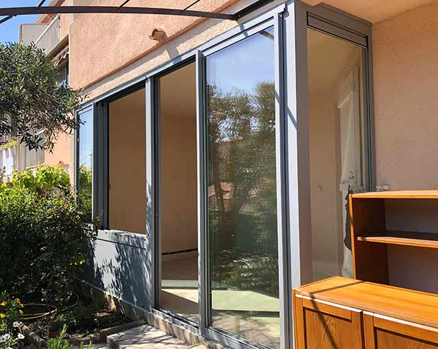 terrasse extérieure fermée avec des fenêtres et portes coulissantes en alu